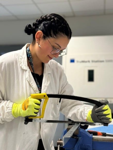 Evaluation of steel coatings to improve corrosion resistance Researcher cutting metal samples in a laboratory to prepare specimens for corrosion testing and steel coating characterization.