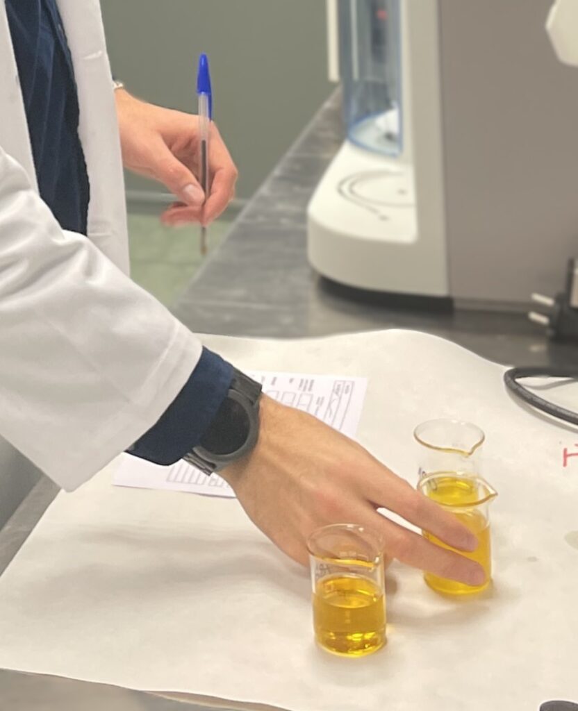 Análisis y evaluación de aceites industriales nuevos y reciclados para la optimización de costes en producción Técnico de laboratorio manipulando muestras de aceite industrial para su caracterización y análisis comparativo.