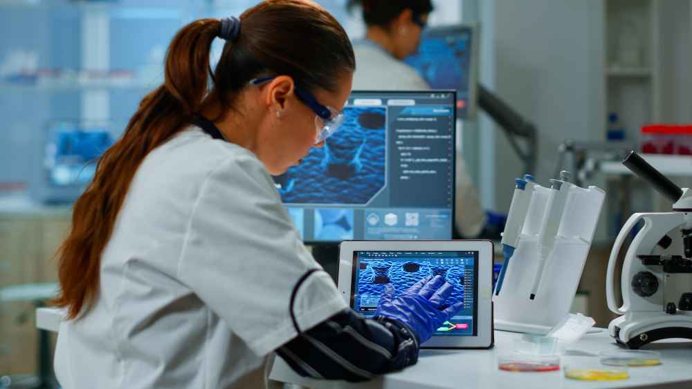 Investigadora analizando muestras de componentes electrónicos en laboratorio para estudiar su resistencia a la corrosión mediante técnicas de caracterización.