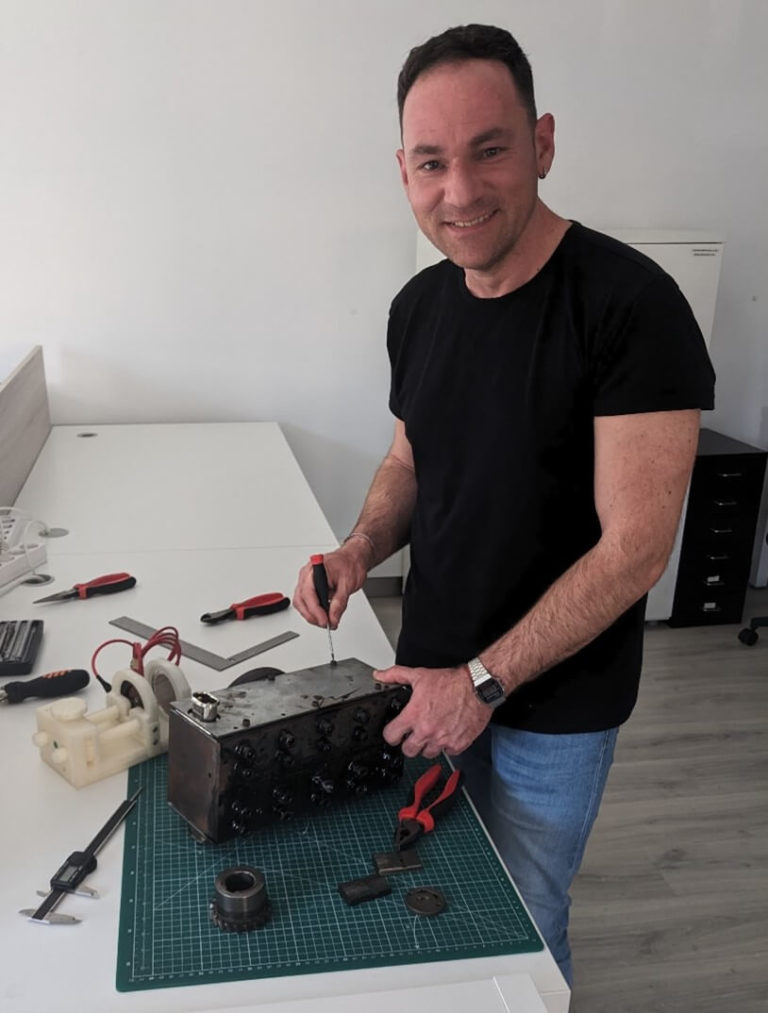 Técnico ajustando un dispositivo mecánico durante el montaje de un setup experimental para ensayo de elongación en conductores eléctricos.
