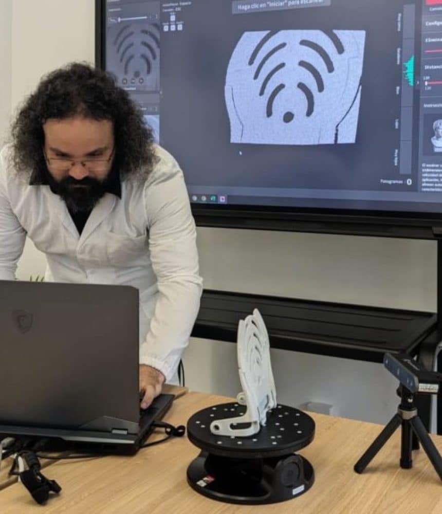 Técnico de Infinitia iniciando escaneado 3D de componente industrial sobre plataforma giratoria con software de captura en pantalla