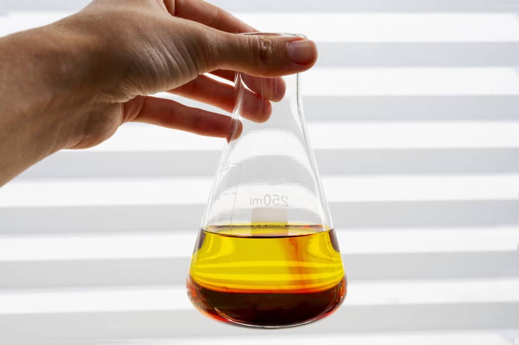 Analysis and evaluation of new and recycled industrial oils for the optimisation of production costs Industrial oil sample in a laboratory flask used for physicochemical analysis and quality evaluation.